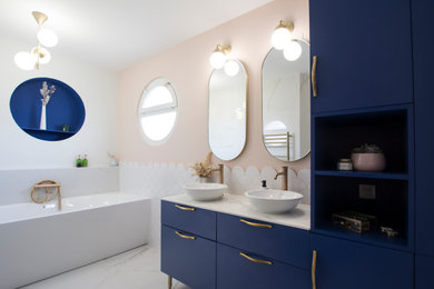 Cette image montre une salle de bain principale vintage de taille moyenne avec des portes de placard bleues, une baignoire encastrée, un carrelage blanc, un carrelage rose, des carreaux de céramique, un mur rose, un sol en marbre, un plan de toilette en marbre, du carrelage bicolore, meuble double vasque et meuble-lavabo sur pied.