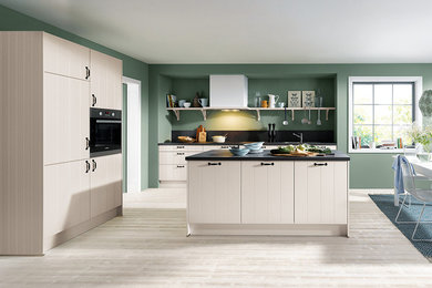 Large farmhouse kitchen/diner in Surrey with grey cabinets, granite worktops, black splashback, stone slab splashback, stainless steel appliances, painted wood flooring and an island.