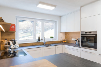 Offene, Mittelgroße Moderne Küche ohne Insel in U-Form mit weißen Schränken, Rückwand aus Holz, grauer Arbeitsplatte und eingelassener Decke in Stuttgart