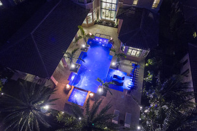 Inspiration for a large contemporary backyard custom-shaped hot tub remodel in Miami with decking