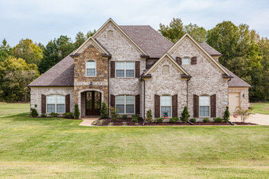 Inspiration for a large timeless beige two-story brick house exterior remodel in Other