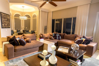 This is an example of a traditional open concept living room in Miami with limestone floors and beige walls.