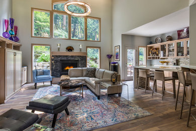 Inspiration for a mid-sized transitional open concept medium tone wood floor and brown floor living room remodel in Other with gray walls, a standard fireplace, a stone fireplace and a media wall