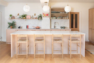 Design ideas for a large contemporary l-shaped open plan kitchen in London with an integrated sink, shaker cabinets, pink cabinets, granite worktops, stainless steel appliances, an island and white worktops.
