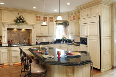 Design ideas for a traditional u-shaped eat-in kitchen in Orlando with an undermount sink, distressed cabinets, with island, raised-panel cabinets, granite benchtops, panelled appliances and light hardwood floors.