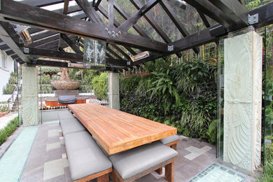 This is an example of a large tropical backyard patio in Los Angeles with an outdoor kitchen, natural stone pavers and a gazebo/cabana.