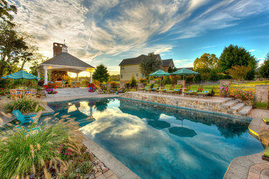 Photo of a large traditional backyard rectangular lap pool in Other with a pool house and concrete pavers.