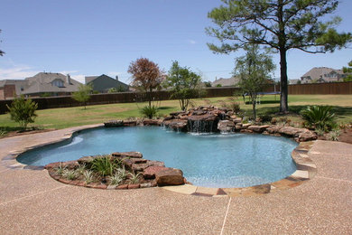 Large traditional backyard custom-shaped pool in Houston with a water feature and stamped concrete.
