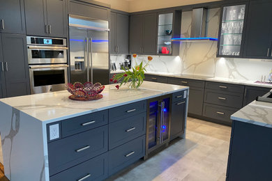 This is an example of a contemporary u-shaped kitchen/diner in San Francisco with a belfast sink, shaker cabinets, grey cabinets, engineered stone countertops, white splashback, engineered quartz splashback, stainless steel appliances, porcelain flooring, an island and white worktops.