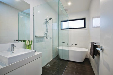 Design ideas for a mid-sized modern kids bathroom in Melbourne with raised-panel cabinets, white cabinets, a freestanding tub, a curbless shower, white tile, ceramic tile, porcelain floors, a drop-in sink, granite benchtops, grey floor, a hinged shower door and white benchtops.