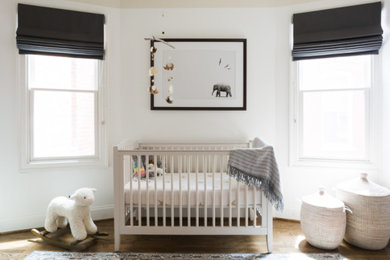 Foto de habitación de bebé neutra clásica renovada con paredes blancas, suelo de madera en tonos medios, suelo marrón y papel pintado