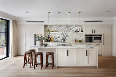 Medium sized scandi single-wall open plan kitchen in London with a built-in sink, shaker cabinets, beige cabinets, marble worktops, white splashback, marble splashback, stainless steel appliances, an island and white worktops.
