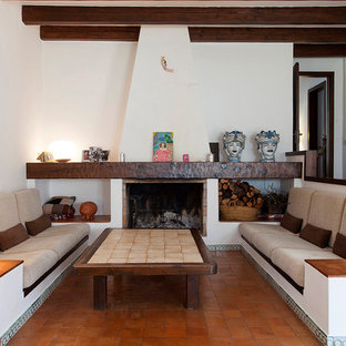 Imagen de biblioteca en casa cerrada, mediterránea, con paredes blancas, suelo de baldosas de terracota y chimenea tradicional