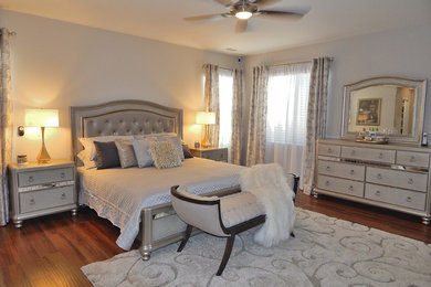 Mid-sized elegant master laminate floor and brown floor bedroom photo in Los Angeles with gray walls, a wood fireplace surround and a standard fireplace