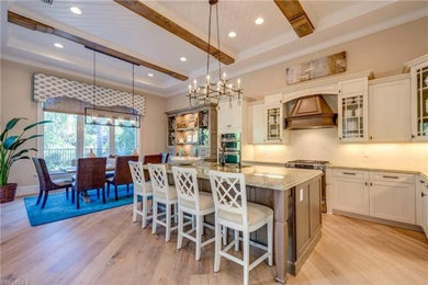 Example of a huge classic l-shaped light wood floor and multicolored floor open concept kitchen design in Baltimore with an undermount sink, recessed-panel cabinets, white cabinets, granite countertops, beige backsplash, ceramic backsplash, stainless steel appliances, an island and multicolored countertops