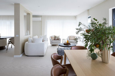 Mid-sized contemporary open concept living room in Sydney with white walls, carpet, a wall-mounted tv and beige floor.