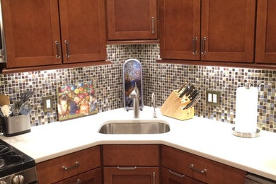 Example of a mid-sized classic u-shaped travertine floor eat-in kitchen design in New York with an undermount sink, shaker cabinets, medium tone wood cabinets, quartz countertops, multicolored backsplash, mosaic tile backsplash, stainless steel appliances and a peninsula