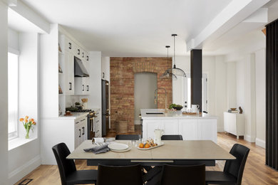 Mid-sized trendy galley vinyl floor and brown floor eat-in kitchen photo in Toronto with an undermount sink, shaker cabinets, white cabinets, quartz countertops, white backsplash, cement tile backsplash, black appliances, an island and white countertops