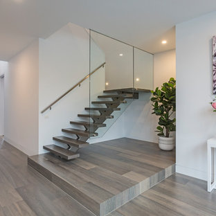 This is an example of a contemporary foyer in Melbourne with white walls, a single front door, a dark wood front door and brown floor.