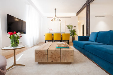 Modelo de salón para visitas abierto contemporáneo grande sin chimenea con paredes blancas, suelo de madera en tonos medios y televisor colgado en la pared
