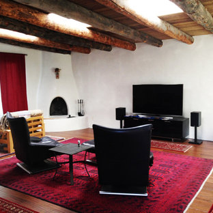 Mittelgroßes, Abgetrenntes Mediterranes Wohnzimmer mit weißer Wandfarbe, Bambusparkett, Eckkamin, verputztem Kaminsims und Wand-TV in Albuquerque