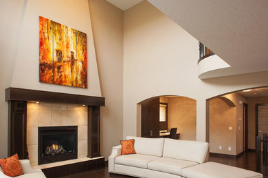 This is an example of a large contemporary open concept living room in Calgary with beige walls, dark hardwood floors, a standard fireplace, a tile fireplace surround and brown floor.
