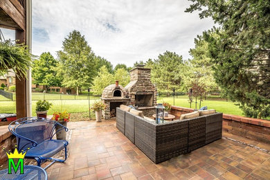 Photo of a large traditional backyard patio in Kansas City with a fire feature and concrete pavers.