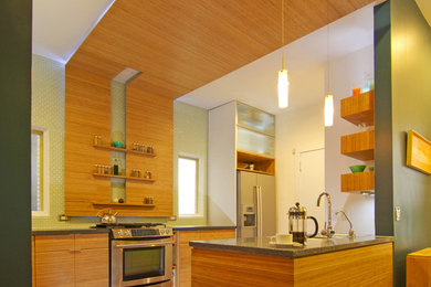 Mid-sized trendy eat-in kitchen photo in Chicago with an undermount sink, flat-panel cabinets, recycled glass countertops, green backsplash, glass tile backsplash, stainless steel appliances and an island