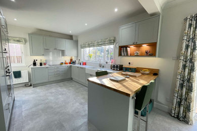 Photo of a medium sized classic u-shaped open plan kitchen in Other with shaker cabinets, grey cabinets, quartz worktops, a breakfast bar, grey floors and white worktops.