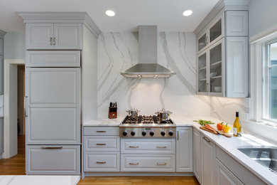 Design ideas for a large transitional l-shaped open plan kitchen in Boston with an undermount sink, raised-panel cabinets, grey cabinets, quartz benchtops, stone slab splashback, panelled appliances, medium hardwood floors and with island.