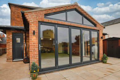 Inspiration for a large and red modern two floor brick and rear extension in Other with a hip roof.