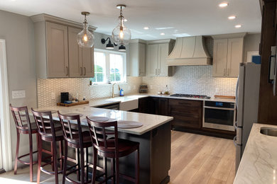 Example of a mid-sized farmhouse u-shaped vinyl floor and brown floor kitchen pantry design in Philadelphia with a farmhouse sink, shaker cabinets, dark wood cabinets, quartzite countertops, white backsplash, mosaic tile backsplash, stainless steel appliances, a peninsula and white countertops