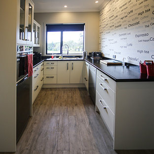 Small contemporary kitchen pantry designs - Inspiration for a small contemporary u-shaped medium tone wood floor and brown floor kitchen pantry remodel in Auckland with a double-bowl sink, flat-panel cabinets, beige cabinets, solid surface countertops, black appliances and no island