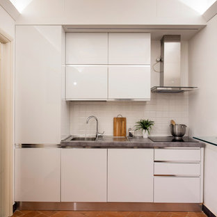 На фото: маленькая линейная кухня в современном стиле с плоскими фасадами, белыми фасадами, белым фартуком, серой столешницей, одинарной раковиной и оранжевым полом без острова с