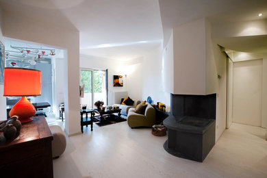 Immagine di un piccolo soggiorno rustico aperto con pareti bianche, parquet chiaro, camino bifacciale, cornice del camino in pietra e pavimento bianco