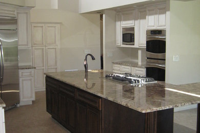 Large elegant u-shaped beige floor open concept kitchen photo in Phoenix with an undermount sink, raised-panel cabinets, white cabinets, granite countertops, stainless steel appliances and an island