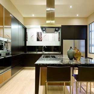 Moderne Küche in L-Form mit Küchengeräten aus Edelstahl, flächenbündigen Schrankfronten, dunklen Holzschränken, Vorratsschrank, Doppelwaschbecken, Granit-Arbeitsplatte, Küchenrückwand in Gelb, Rückwand aus Porzellanfliesen, hellem Holzboden und Kücheninsel in Auckland