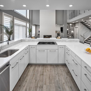 Idées déco pour une arrière-cuisine contemporaine en U de taille moyenne avec un évier encastré, un placard à porte persienne, des portes de placard blanches, un plan de travail en quartz modifié, une crédence blanche, un électroménager en acier inoxydable, un sol en bois clair, un îlot central, un sol marron et un plan de travail blanc.