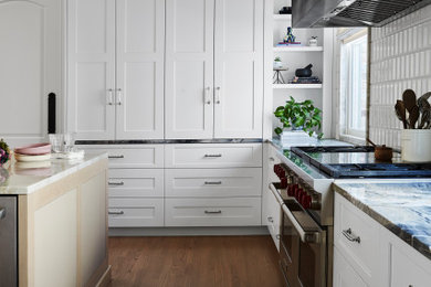 Cette image montre une grande cuisine ouverte traditionnelle avec des portes de placard blanches, un plan de travail en quartz et îlot.