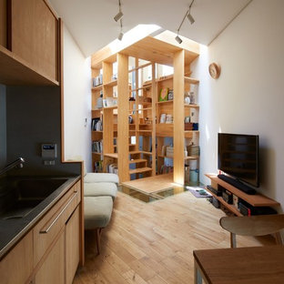 Bild på ett litet funkis allrum med öppen planlösning, med vita väggar, ljust trägolv, en fristående TV och brunt golv