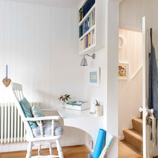 Maritim inredning av ett litet arbetsrum, med vita väggar, mellanmörkt trägolv och ett inbyggt skrivbord