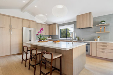 Inspiration for a contemporary l-shaped light wood floor open concept kitchen remodel in San Francisco with flat-panel cabinets, light wood cabinets, quartzite countertops, blue backsplash, ceramic backsplash, stainless steel appliances, an island and beige countertops