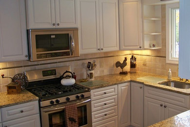 Kitchen - mid-sized traditional kitchen idea in Boston with an undermount sink, raised-panel cabinets, white cabinets, granite countertops, beige backsplash, stone tile backsplash and stainless steel appliances