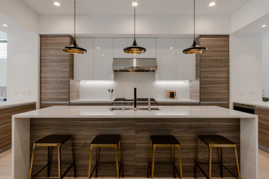 Design ideas for a large modern u-shaped open plan kitchen in Chicago with a single-bowl sink, flat-panel cabinets, medium wood cabinets, quartz benchtops, white splashback, engineered quartz splashback, stainless steel appliances, light hardwood floors, with island, white floor and white benchtop.