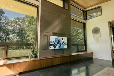 Foto de salón con rincón musical abierto moderno grande con paredes grises, suelo de cemento, televisor colgado en la pared, suelo gris y madera
