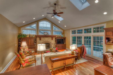 Example of a mid-sized classic enclosed medium tone wood floor family room design in Milwaukee with yellow walls, a ribbon fireplace, a stone fireplace and a media wall