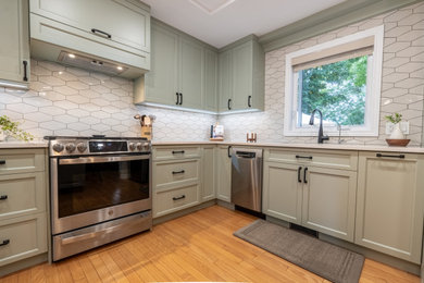 Kitchen - small contemporary medium tone wood floor and brown floor kitchen idea in Ottawa with an undermount sink, shaker cabinets, green cabinets, quartz countertops, white backsplash, ceramic backsplash, stainless steel appliances, an island and white countertops