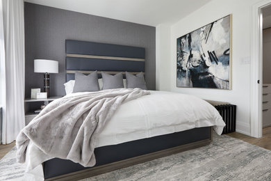 Example of a mid-sized trendy master medium tone wood floor and wallpaper bedroom design in Toronto with white walls