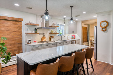 Inspiration for a mid-sized transitional laminate floor and brown floor kitchen remodel in Other with shaker cabinets, beige cabinets, quartz countertops, white backsplash, ceramic backsplash, stainless steel appliances and white countertops