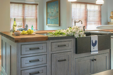 Inspiration for a mid-sized country galley open plan kitchen in Boston with a farmhouse sink, beaded inset cabinets, white cabinets, wood benchtops, blue splashback, cement tile splashback, panelled appliances, medium hardwood floors, with island, brown floor and black benchtop.